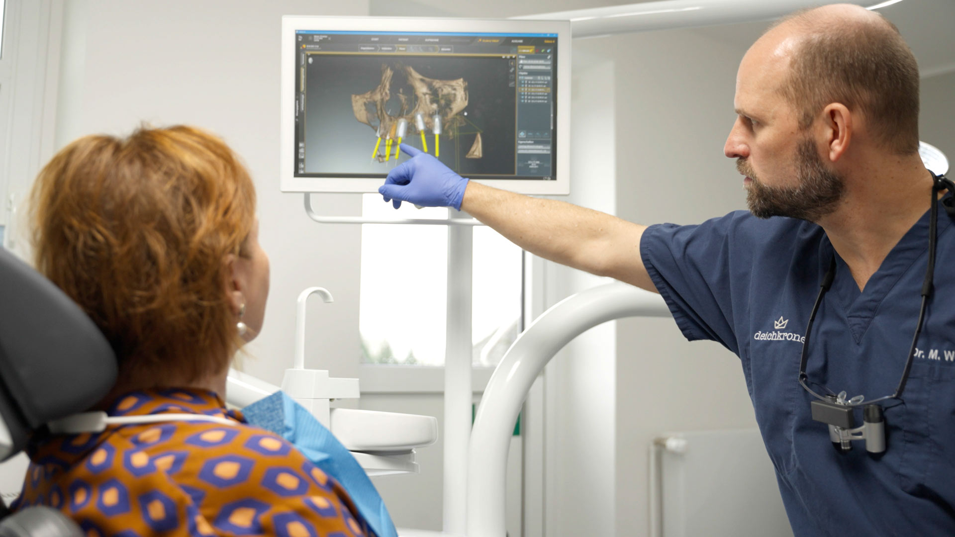 Zahnarzt erklärt Patientin 3D-Röntgenaufnahme am Bildschirm
