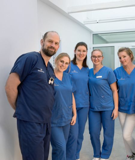 Team des Zahnzentrums Deichkrone steht gemeinsam lächelnd in der Praxis