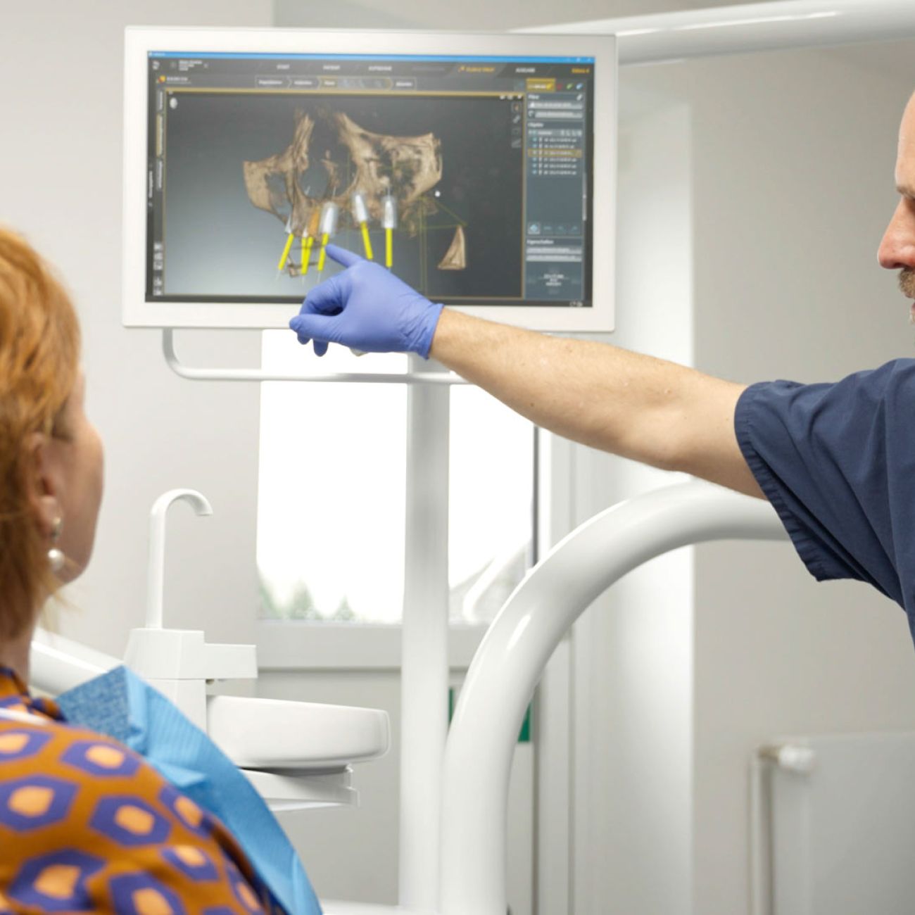 Zahnarzt erklärt Patientin 3D-Röntgenaufnahme am Bildschirm